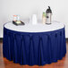 A table with a royal blue Snap Drape table skirt and a tray of coffee cups.