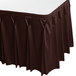 A brown Snap Drape Wyndham table skirt with bow tie pleats on a table.
