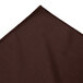 A close up of a brown Snap Drape Wyndham table skirt with a pleated edge.