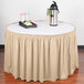 A cream shirred pleat table skirt with Velcro clips on a table with a tray of food and drinks.