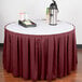 A round table with a burgundy Snap Drape table skirt and a tray of coffee and a container.