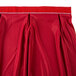 A red Snap Drape table skirt with pleated bow tie detailing and a red band.
