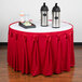 A table with a Snap Drape red table skirt and two metal containers on it.