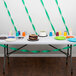 A table with a chocolate cake and cups on it with Emerald Green Streamer Paper on the table.