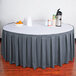 A table with a slate blue Snap Drape box pleat table skirt on it with a bowl of fruit.