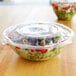 A salad in a clear Eco-Products compostable plastic bowl with a lid.
