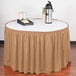 A table with a Snap Drape Wyndham Sandalwood shirred pleat table skirt on it and a tray of food.