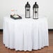 A table with a white Snap Drape table skirt and two metal containers on it.