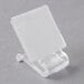 A white square table skirt clip with a clear plastic Snap Drape clip.