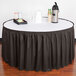 A charcoal Snap Drape table skirt on a table with a black and white tablecloth.