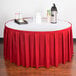 A table with a red Snap Drape table skirt and a tray of drinks.