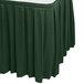 A green Snap Drape Wyndham box pleat table skirt on a table with a white surface.