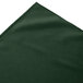 A close-up of a dark green Snap Drape box pleat table skirt with a corner.
