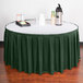 A table with a Snap Drape jade box pleat table skirt on a green table with a tray of drinks.
