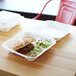 A hamburger and salad in a white Eco-Products compostable takeout container.