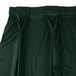 A close up of a dark green Snap Drape Wyndham bow tie pleat table skirt.