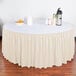 A table with a Snap Drape bone shirred pleat table skirt on it and a bowl of oranges.