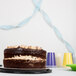 A chocolate cake with blue streamer paper on a table.