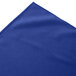 A royal blue box pleat table skirt on a table with a white background.