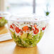 A salad in a 48 oz. clear compostable plastic salad bowl with a lid.