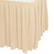 A cream Snap Drape box pleat table skirt on a table with a white tablecloth.