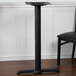 A BFM Seating sand black stamped steel table base with a black table and chair.