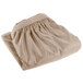 A folded beige table skirt on a white background.