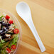 A bowl of salad with a white Eco-Products compostable plastic serving spoon in it.