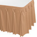 A tan Snap Drape Wyndham table skirt with pleated edges on a table.