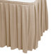 A beige Snap Drape table skirt with pleated edges on a table.