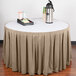 A table with a beige Snap Drape box pleat table skirt with Velcro clips on it and a tray of coffee cups.