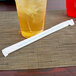 A glass of yellow liquid with ice and a Eco-Products clear wrapped compostable plastic straw.