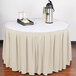 A table with a Snap Drape Wyndham bone box pleat table skirt on it with a tray of coffee cups.