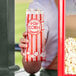 A person holding a Carnival King popcorn bag full of popcorn.
