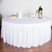 A table with a white Snap Drape table skirt on it and a bowl of fruit.