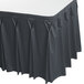 A slate blue Snap Drape Wyndham table skirt with bow tie pleats on a table.