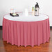 A table with a Snap Drape dusty rose box pleat table skirt and a tray of drinks.