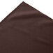 A brown cloth table skirt with box pleats on a white background.
