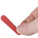A person holding a red Basic Earth Botanicals nail file.
