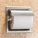 A Bobrick recessed stainless steel toilet paper holder with a roll of toilet paper.