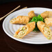 A white round melamine plate with fried spring rolls on it.