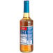 A Torani Sugar-Free Caramel Flavoring Syrup 750 mL glass bottle with a blue label.