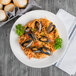 A plate of spaghetti with mussels and parsley in a white Libbey Elan porcelain bowl.