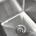 A close-up of the drain in an Advance Tabco stainless steel two compartment sink.