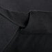 A close up of a black poly-cotton Chef Revival bib apron with a pocket.