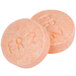 A close-up of two orange Medi-First pain relief tablets with writing on them.