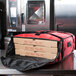 A stack of pizza boxes in a red Rubbermaid pizza delivery bag.