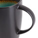 A close-up of a black Libbey stoneware coffee mug with a green rim.