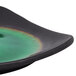A close up of a Libbey Hakone square stoneware plate with round detailing and a black and green rainbow rim.