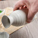 A hand pouring liquid into a white Libbey stoneware jug.